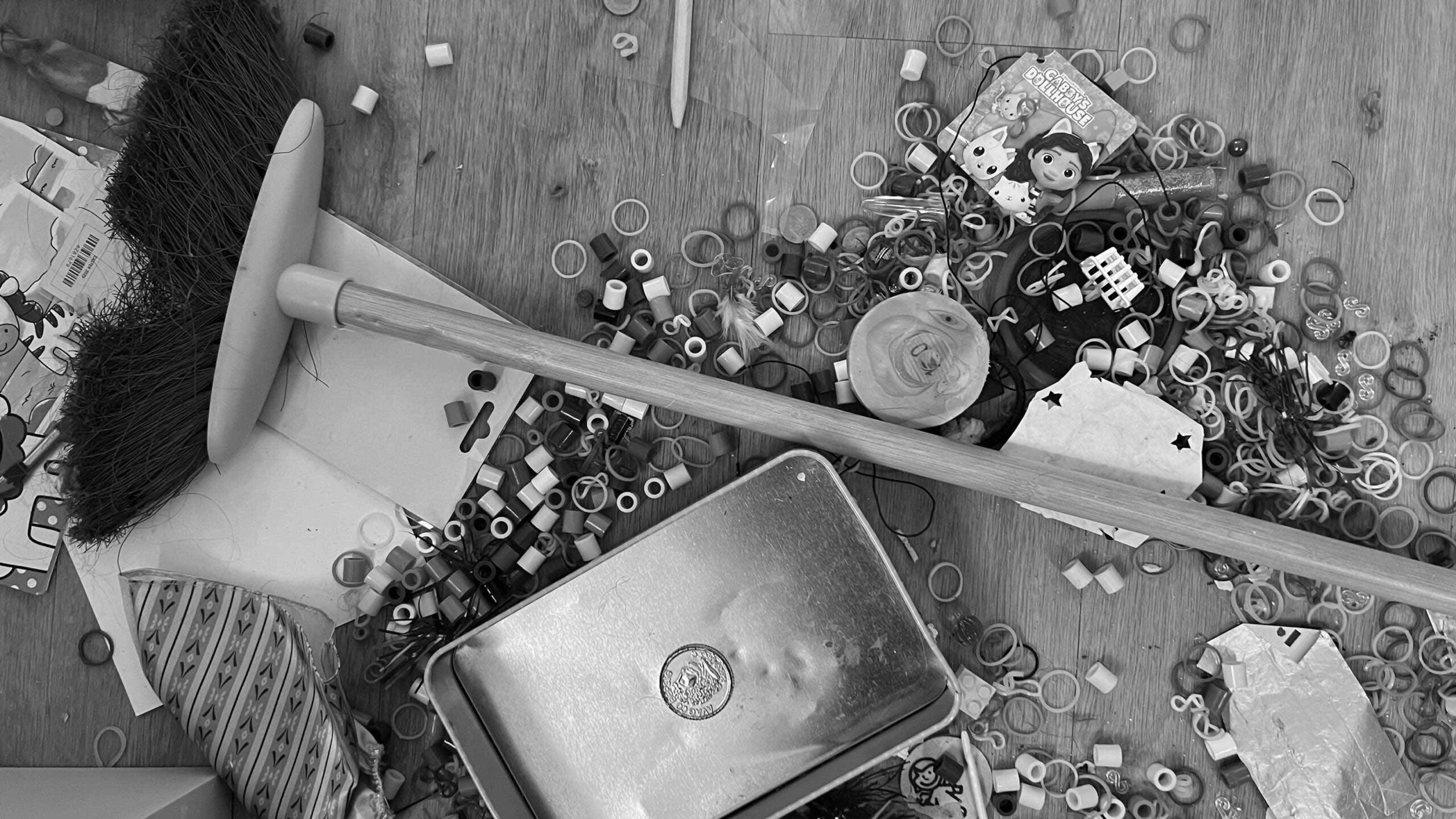 Chaos auf dem Boden einer Wohnung mit verstreuten Gegenständen und Besen als Symbol für chronische Unordnung und Überforderung im Alltag.